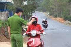 Đo thân nhiệt người điều khiển phương tiện giao thông tại chốt kiểm dịch. (Ảnh: Đặng Tuấn/TTXVN)