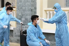 Đo kiểm tra thân nhiệt và làm thủ tục tiếp nhận hành khách về từ Đà Nẵng tại khu cách ly tập trung Trường quân sự Bộ Tư lệnh Thủ đô. (Ảnh: Minh Quyết/TTXVN)