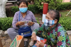 Người bán vé số dạo ở Bình Dương vui mừng nhận quà hỗ trợ. (Ảnh: Nguyễn Văn Việt/TTXVN)