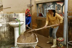 Phụ huynh học sinh cùng giáo viên nhà trường dọn vệ sinh khuôn viên trường học để học sinh nhanh chóng trở lại học tập. (Ảnh: Quốc Khánh/TTXVN)