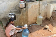 Các em nhỏ lấy nước vào can nhựa từ đường ống cấp nước của chính phủ ở ngoại ô Hyderabad, Ấn Độ. (Nguồn: AFP/TTXVN)