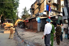 Lực lượng chức năng tiến hành phá bỏ phần diện tích của cửa hàng lấn chiếm vỉa hè trên phố Lương Định Của. (Ảnh: Thành Đạt/TTXVN)