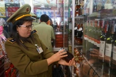 Lực lượng quản lý thị trường kiểm tra một cửa hàng kinh doanh rượu. (Ảnh: Phạm Cường/TTXVN)