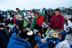 Nhân viên tình nguyện phân phát thực phẩm cho những người di cư đợi xe buýt để vào sâu trong lãnh thổ Áo tại Nickelsdorf khu vực biên giới Áo và Hungary ngày 5/9. (Nguồn: AFP/TTXVN)