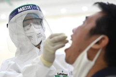 Nhân viên y tế tiến hành lấy mẫu dịch hầu họng để xét nghiệm bằng phương pháp RT-PCR. (Ảnh: Thành Đạt/TTXVN)