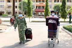 Các chiến sỹ trường Quân sự Quân khu 7 hỗ trợ vận chuyển đồ cho công dân đã hoàn thành xong thời gian cách ly y tế. (Ảnh: Xuân Khu/TTXVN)