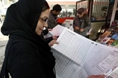Một phụ nữ đang xem danh sách ứng cử viên bị cáo buộc liên quan đến đảng Baath. (Ảnh: AFP)