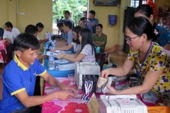 Người dân thôn Vịnh Mốc làm thủ tục nhận tiền đền bù sự cố môi trường biển. (Ảnh: Trần Tĩnh/TTXVN)