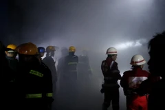 Lính cứu hỏa làm nhiệm vụ tại hiện trường vụ nổ trên phố Tharyar rạng sáng 21/11. (Nguồn: EPA/TTXVN)