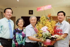 Bí thư Thành ủy Đinh La Thăng tặng hoa chúc mừng Nhà giáo nhân dân Phạm Chánh Trực. (Ảnh: Phương Vy/TTXVN)