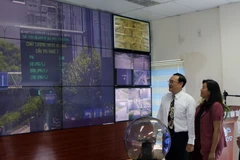 Đại diện lãnh đạo các đơn vị và đại biểu xem thông tin về chất lượng môi trường trên bảng thông tin giao thông điện tử. (Ảnh: Hoàng Hải/TTXVN)
