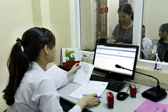 Làm thủ tục khám, chữa bệnh có bảo hiểm y tế. (Ảnh: Dương Ngọc/TTXVN)