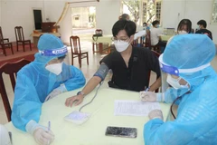 Khám sàng lọc trước khi tiêm vaccine cho sinh viên tại điểm tiêm Trường Đại học Trà Vinh. (Ảnh: Thanh Hòa/TTXVN)