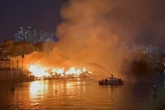 Cảnh sát Phòng cháy chữa cháy sử dụng canô chuyên dụng phun nước vào đám cháy. (Ảnh: TTXVN)