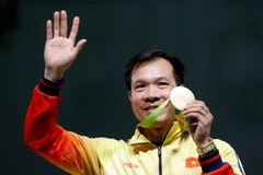 Xạ thủ Hoàng Xuân Vinh cùng tấm huy chương Vàng lịch sử. (Nguồn: EPA/TTXVN)