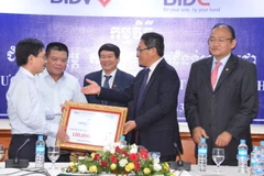 Đại diện BIDV trao trượng trưng 100.000 USD cho Bộ trưởng Sok Chenda. (Ảnh: Chí Hùng/Vietnam+)