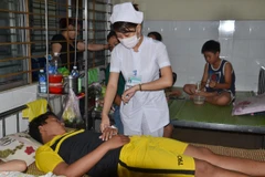 Bác sỹ của Trung tâm y tế quận Liên Chiểu điều trị cho bệnh nhân sốt xuất huyết. (Ảnh: Đinh Văn Nhiều/TTXVN)