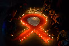 Những người tình nguyện xếp nến thành hình ruybăng đỏ nhân Ngày Thế giới phòng chống AIDS (1/12) tại Siliguri, Ấn Độ. (Ảnh: AFP/TTXVN)
