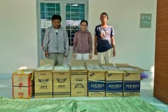 Các đối tượng vận chuyển, mua bán số lượng lớn thuốc lá điếu nhập lậu bị bắt giữ cùng tang vật. (Ảnh: TTXVN phát)