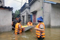 Các cô giáo trường mầm non Thanh Nghị (huyện Thanh Liêm) tổ chức nấu cơm và đi phát cho người dân trong lũ. (Ảnh: Đại Nghĩa/TTXVN)