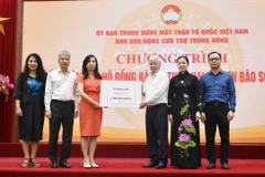 Chủ tịch Ủy ban Trung ương Mặt trận Tổ quốc Việt Nam Đỗ Văn Chiến tiếp nhận bảng tượng trưng số tiền từ Thứ trưởng Bộ Ngoại giao, Chủ nhiệm Ủy ban Nhà nước về người Việt Nam ở nước ngoài Lê Thị Thu Hằng. (Ảnh: TTXVN phát)