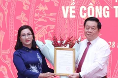 Trưởng Ban Tuyên giáo Trung ương Nguyễn Trọng Nghĩa trao quyết định cho bà Đinh Thị Mai. (Ảnh: Phương Hoa/TTXVN)