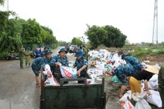Lực lượng chức năng cùng người dân xã Đại Áng (huyện Thanh Trì, Hà Nội) chuẩn bị gần 10.000 bao tải cát, đóng cọc để gia cố đê tả sông Nhuệ đoạn qua Trạm bơm Hòa Bình. (Ảnh: TTXVN phát)