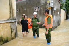 Lực lượng chức năng hỗ trợ người dân đến nơi an toàn. (Ảnh: Đỗ Huyền/TTXVN)