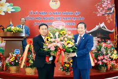 Đại sứ Việt Nam tại Lào Nguyễn Bá Hùng tặng hoa chúc mừng 15 năm thành lập Tổng hội. (Ảnh: Phạm Kiên/TTXVN)