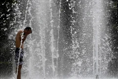 Người dân làm mát tại một đài phun nước ở Seville, Tây Ban Nha. (Ảnh: AFP/TTXVN)