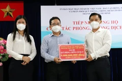 Ông Phạm Minh Tuấn, Phó Chủ tịch Ủy ban MTTQ Việt Nam Thành phố Hồ Chí Minh (giữa) tiếp nhận tượng trưng kinh phí ủng hộ công tác phòng, chống dịch từ Tổng Công ty Điện lực Thành phố Hồ Chí Minh. (Ảnh: Xuân Khu/TTXVN)