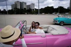 Du khách nước ngoài chụp ảnh với xe cổ tại thủ đô La Havana, Cuba. (Nguồn: Reuters)