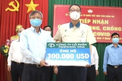 Chủ tịch UBND tỉnh Đồng Nai Cao Tiến Dũng (trái) tiếp nhận 300.000 USD từ Đại diện Công ty cổ phần Taekwang Vina ủng hộ Quỹ vaccine phòng, chống dịch COVID-19. (Ảnh: TTXVN phát)