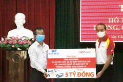 Đại diện Tập đoàn Sovico và Ngân hàng Thương mại Cổ phần Phát triển Thành phố Hồ Chí Minh HDBank (phải) trao bảng tượng trưng tăng tỉnh An Giang 1 xe cấp cứu, 5 máy thở cao cấp, 2.500 bộ quần áo bảo hộ y tế. (Ảnh: Công Mạo/TTXVN)