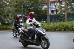 Người dân khi ra đường nên mặc ấm, đeo khẩu trang và mang theo áo mưa đề phòng những cơn mưa. (Ảnh: Tuấn Đức/TTXVN)