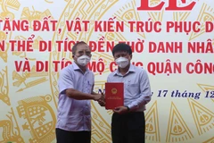 Ông Trần Đức Nghị, Trưởng gia tộc Trần Đức, trao sổ đỏ 1.800m2 đất cho đại diện lãnh đạo thị xã Hoài Nhơn. (Ảnh: Phạm Kha/TTXVN)