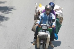 Thời điểm giữa trưa, nếu phải di chuyển trên đường, người dân cần trang bị đồ chống nắng để đảm bảo sức khỏe. (Ảnh: Thanh Tùng/TTXVN)