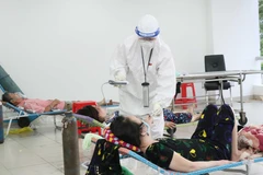 Các bác sỹ thăm khám bệnh nhân nhiễm COVID-19 không triệu chứng có bệnh nền tại Bệnh viện dã chiến thu dung điều trị COVID-19 số 3, thành phố Thủ Đức. (Ảnh: Xuân Khu-TTXVN)