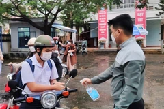 Học sinh trường THPT Hoàng Hoa Thám xịt sát khuẩn tay tại cổng trường. (Ảnh: Văn Dũng/TTXVN)