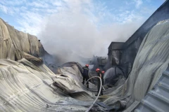 Lực lượng Phòng cháy chữa cháy tiếp cận hiện trường để dập lửa. (Ảnh: Huỳnh Phúc Hậu/TTXVN)