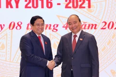 Chủ tịch nước Nguyễn Xuân Phúc, nguyên Thủ tướng Chính phủ chúc mừng Thủ tướng Chính phủ Phạm Minh Chính. (Ảnh: TTXVN)