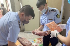 Lực lượng chức năng kiểm tra số hàng bị thu giữ. (Ảnh: TTXVN phát)