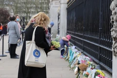 Người dân London đến đặt hoa tưởng niệm Hoàng thân Philip dọc theo cổng của Cung điện Buckingham. (Ảnh: Hải Vân/TTXVN)