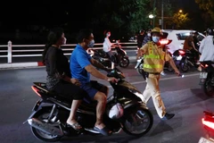 Tổ công tác Y12/141 dừng xe và kiểm tra trường hợp không đội mũ bảo hiểm khi tham gia giao thông. (Ảnh: Phạm Kiên/TTXVN)