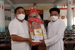 Chủ tịch Ủy ban Mặt trận Tổ quốc Việt Nam tỉnh, Trưởng ban Dân vận tỉnh Cà Mau Trần Văn Hiện (trái) tặng quà chúc mừng chức sắc, chức việc Hội thánh Cao đài Minh Chơn Đạo (ấp Xóm Sở, xã Hồ Thị Kỷ, huyện Thới Bình). (Ảnh: Kim Há/TTXVN)