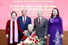 Chủ tịch nước Nguyễn Xuân Phúc và các đại biểu tại Lễ trao tặng huy hiệu 75 năm tuổi Đảng cho bà Nguyễn Thị Bình, nguyên Ủy viên Trung ương Đảng, nguyên Phó Chủ tịch nước CHXHCN Việt Nam. (Ảnh: Thống Nhất/TTXVN)