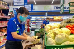 Nhân viên siêu thị Thành phố Hồ Chí Minh bổ sung hàng hóa lên kệ phục vụ khách hàng mua sắm trực tiếp. (Ảnh: TTXVN phát)