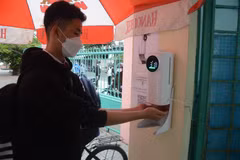 Học sinh lớp 8, 9 trường Trung học cơ sở Hoàng Sa (quận Thọ Quang) đo thân nhiệt và rửa tay bằng nước sát khuẩn tại cổng trường. (Ảnh: Văn Dũng/TTXVN)