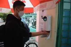 Học sinh lớp 8, 9 trường Trung học cơ sở Hoàng Sa (quận Thọ Quang) đo thân nhiệt và rửa tay bằng nước sát khuẩn tại cổng trường. (Ảnh: Văn Dũng/TTXVN)
