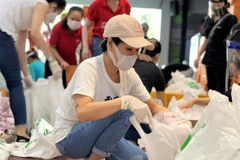 Ca sỹ Uyên Linh đóng gói nhu yếu phẩm để trao cho người dân gặp khó khăn do COVID-19. (Nguồn: tuoitre.vn)